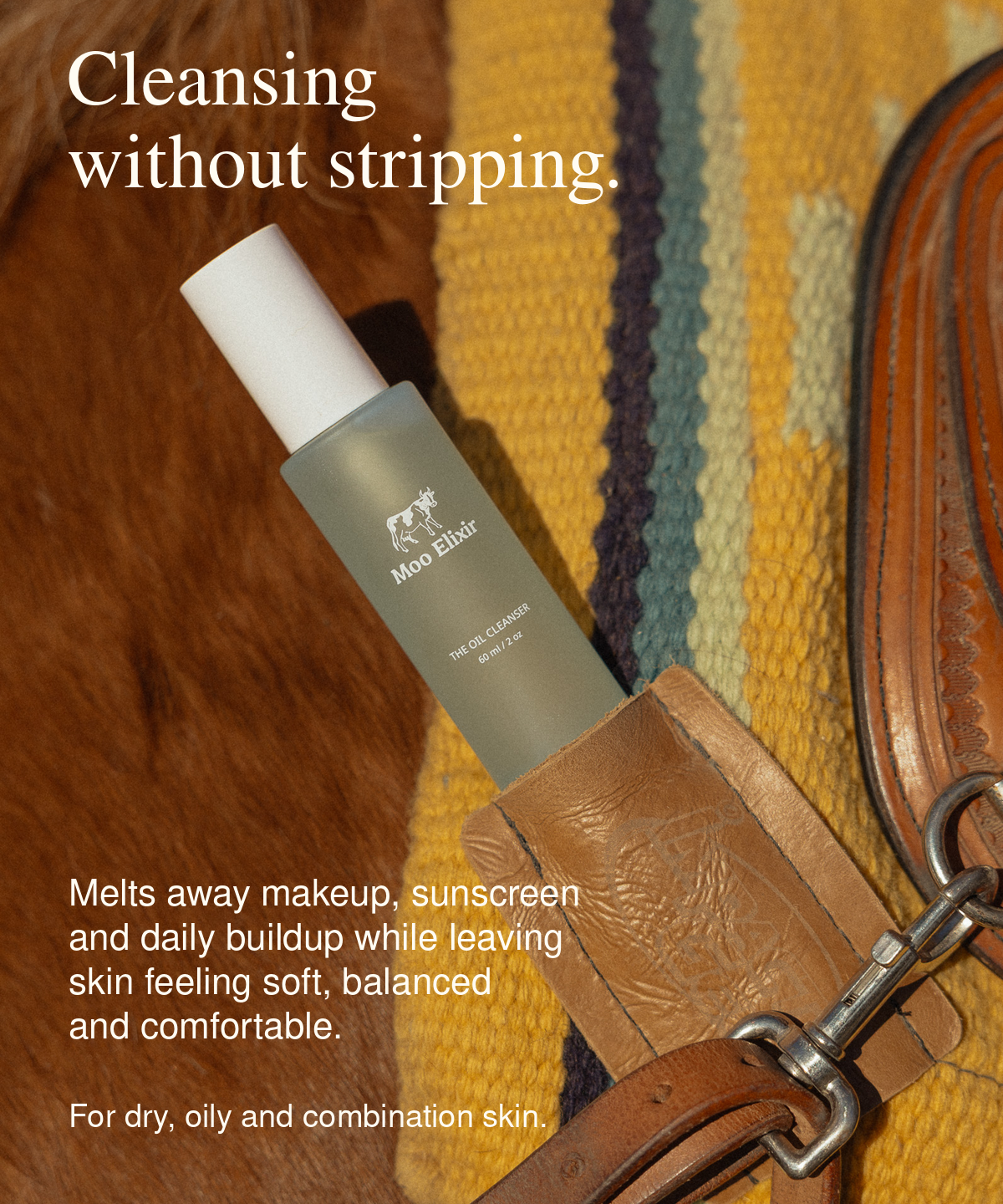 A bottle of Miso Elixir Oil Cleanser lies on a textured yellow and blue striped blanket with brown leather and fur props. White text overlays describe the product as melting away makeup, sunscreen, and daily buildup while leaving skin feeling soft, balanced, and comfortable.